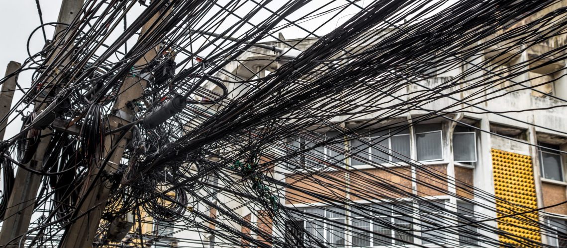 Messy wires attached to the electric pole, the chaos of cables and wires on an electric pole in Bangkok, Thailand, concept of electricity